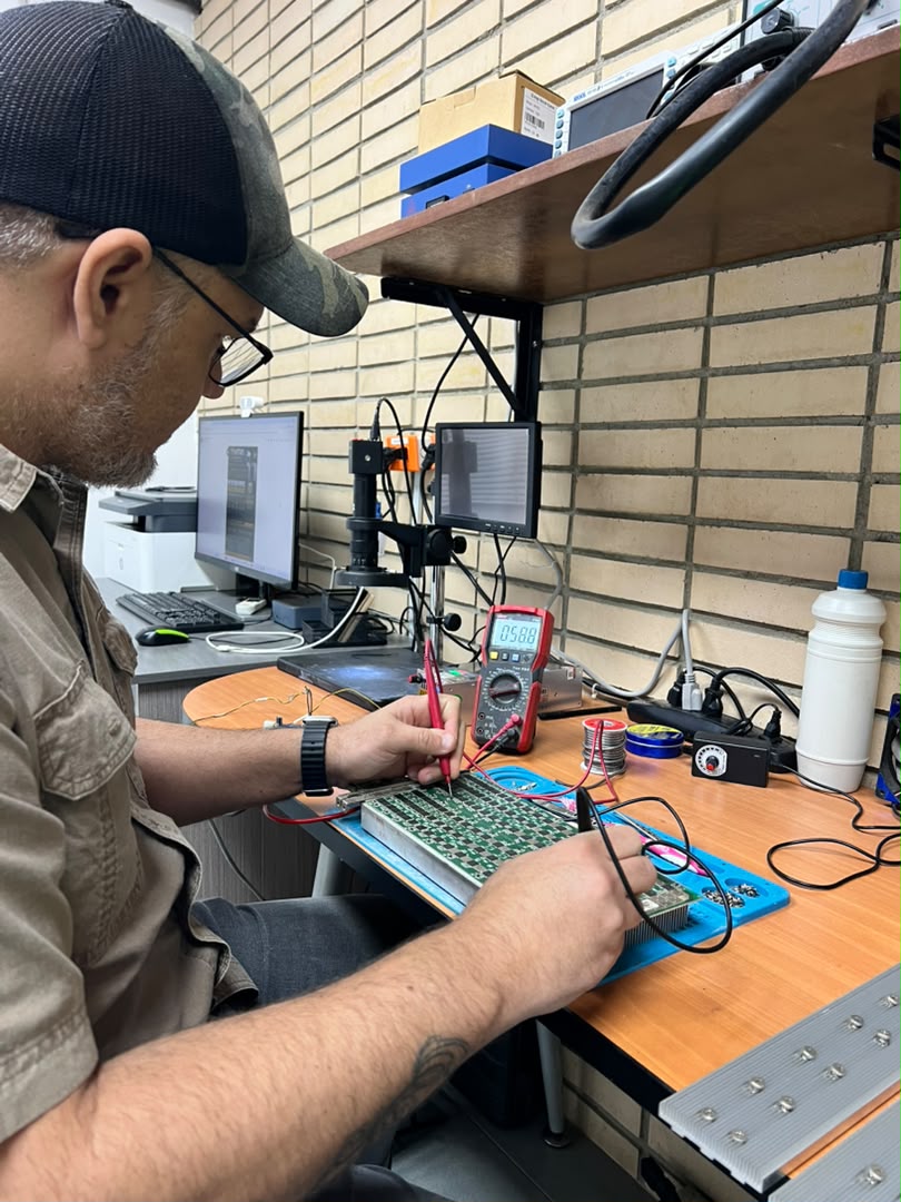 Astro Solutions technician diagnosing an ASIC hashboard with a multimeter at the repair bench