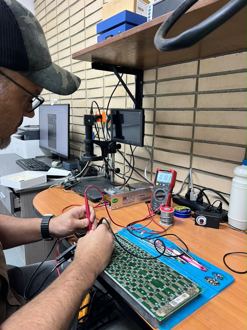 Technician diagnosing an ASIC miner hashboard with bench power supply and multimeter at the Astro Solutions lab